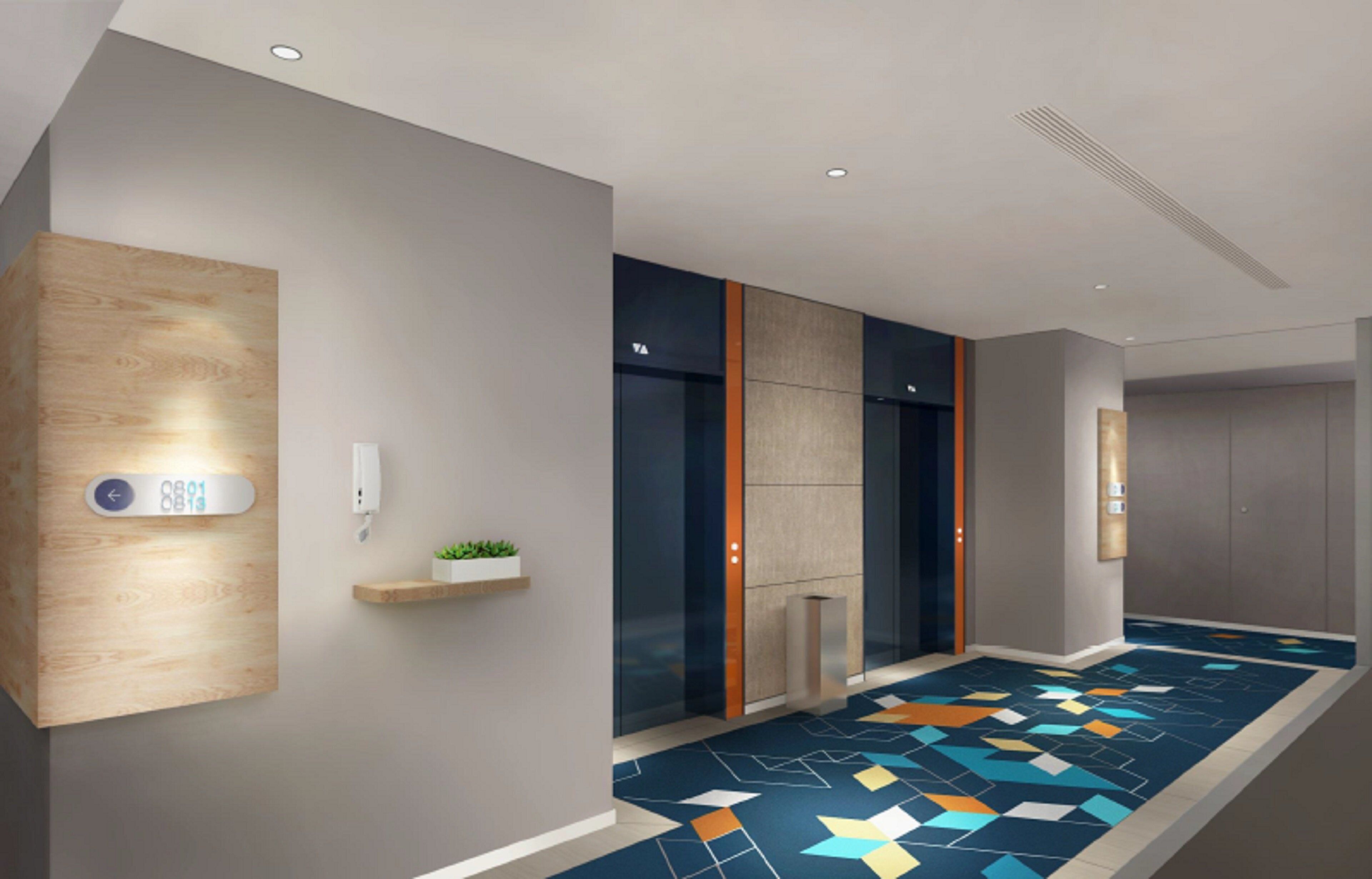 A modern hallway with a digital display, a plant on a shelf, and a patterned floor.