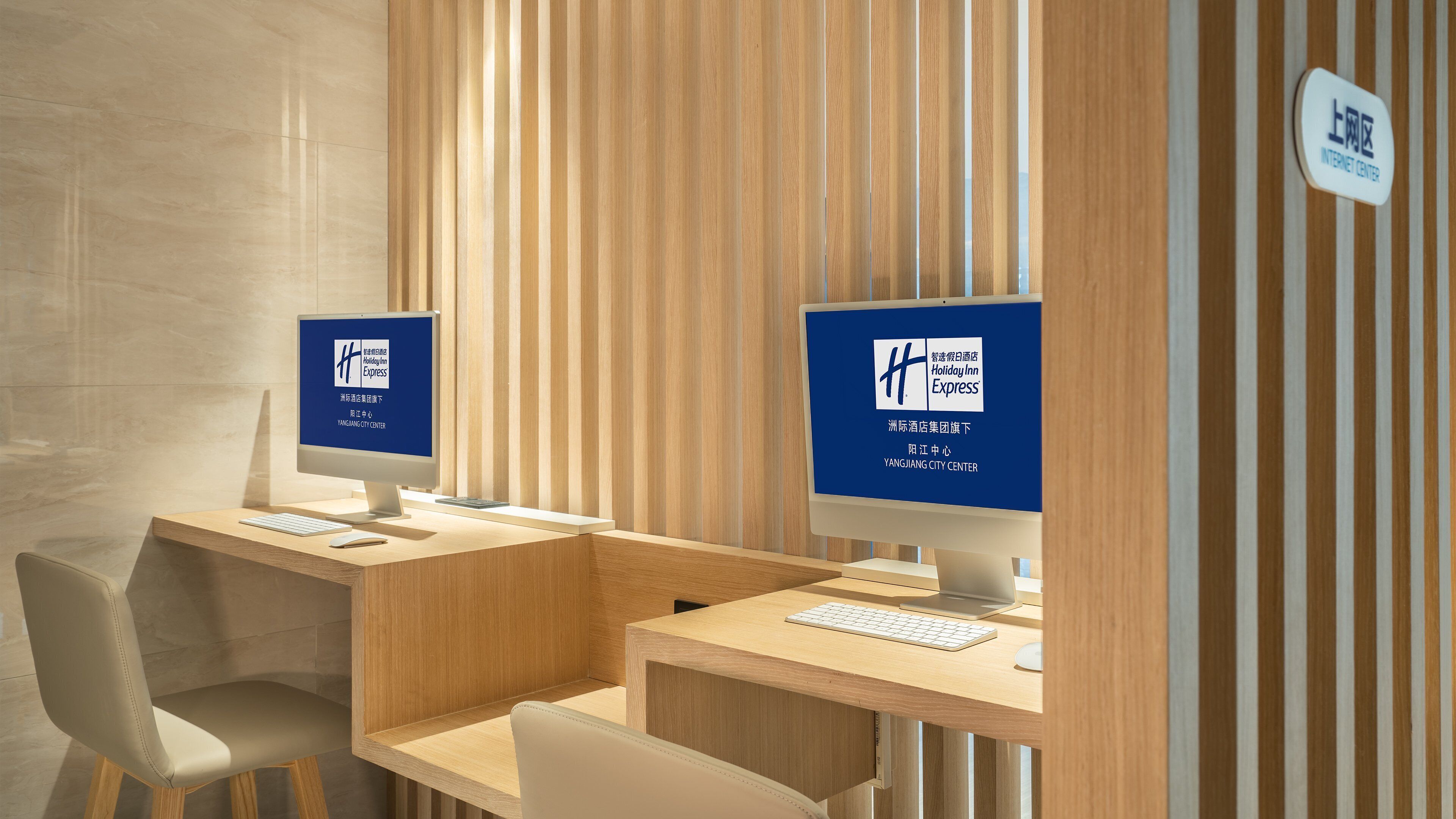 Um hall de hotel moderno com duas estações de computador, cada uma exibindo o logotipo Holiday Inn Express, e uma placa indicando a localização como Centro da Cidade de Yangjiang.