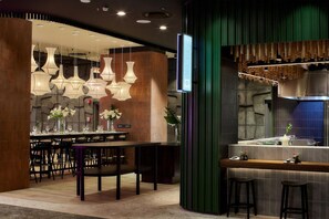 A restaurant interior with a bar area, multiple hanging pendant lights, and a green accent wall. - The Rockefeller Hotel by Newmark (Cape Town)