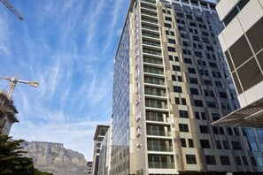 A multi-story building with a modern architectural design, featuring a prominent glass facade and a series of balconies.