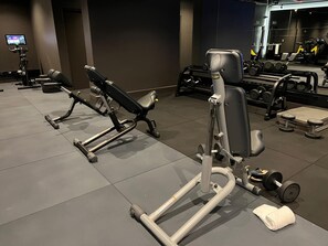 A gym with exercise equipment, including a bench press, a leg press, and dumbbells. - The Rockefeller Hotel by Newmark (Cape Town)