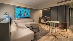 A modern living room with a sofa, round coffee table, and two chairs. There is a kitchen area in the background with a dining table and chairs.