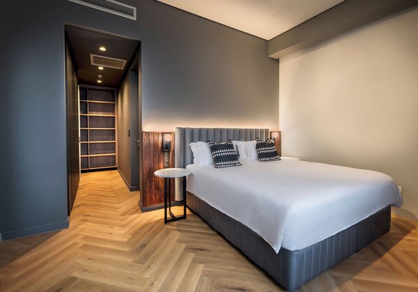 A modern bedroom with a large bed, a nightstand, and a built-in wardrobe.