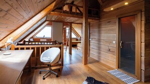 A wooden cabin with a loft bedroom, a desk with a chair, and a large window. - Pure nature with amazing view (Podjelje)