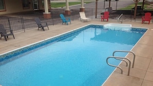 Una piscina rectangular con borde de azulejos y escalera de metal.