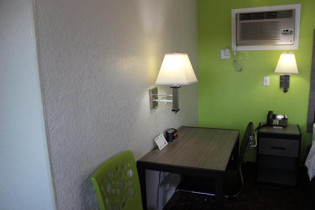 Una habitación pequeña con escritorio, dos lámparas de pared, teléfono y calentador.