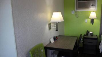 Una habitación pequeña con escritorio, dos lámparas de pared, teléfono y calentador.