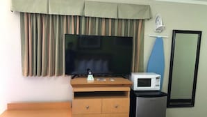 Habitación de hotel con un escritorio de madera, televisor de pantalla plana, microondas y refrigerador compacto.