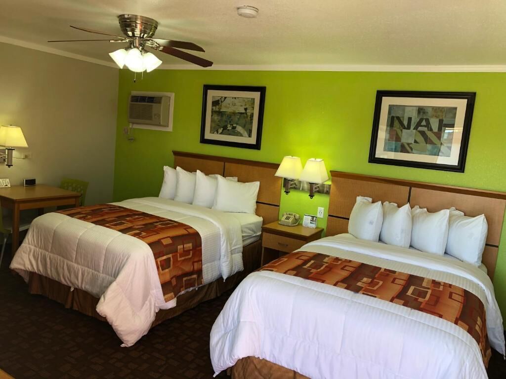 A hotel room with two beds, a ceiling fan, and two bedside tables with lamps.