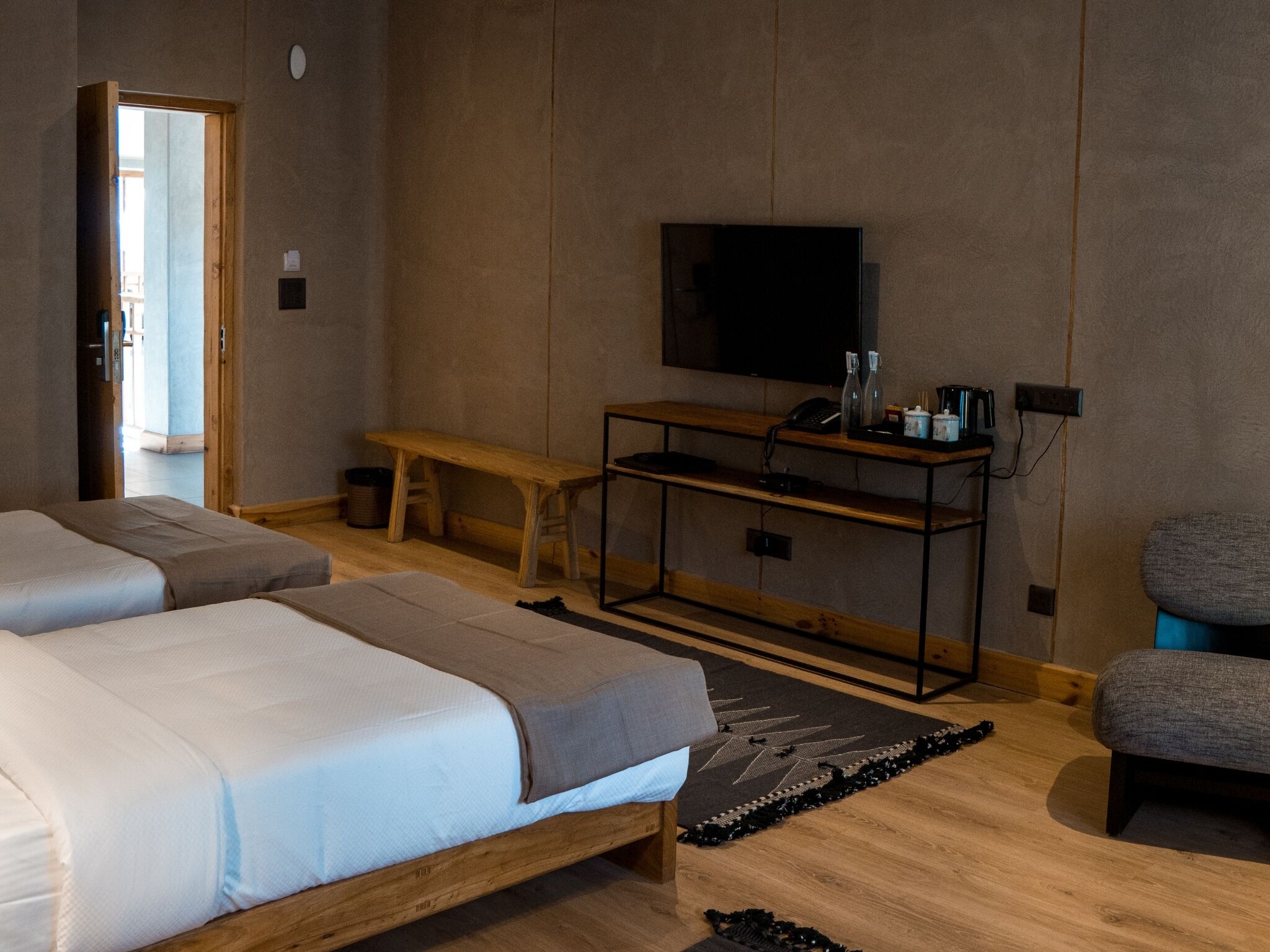Habitación de hotel con dos camas, televisión, escritorio y una banca.