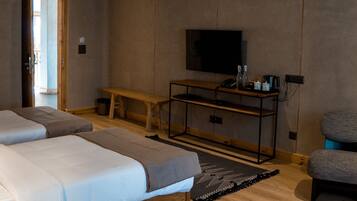 Habitación de hotel con dos camas, televisión, escritorio y una banca.