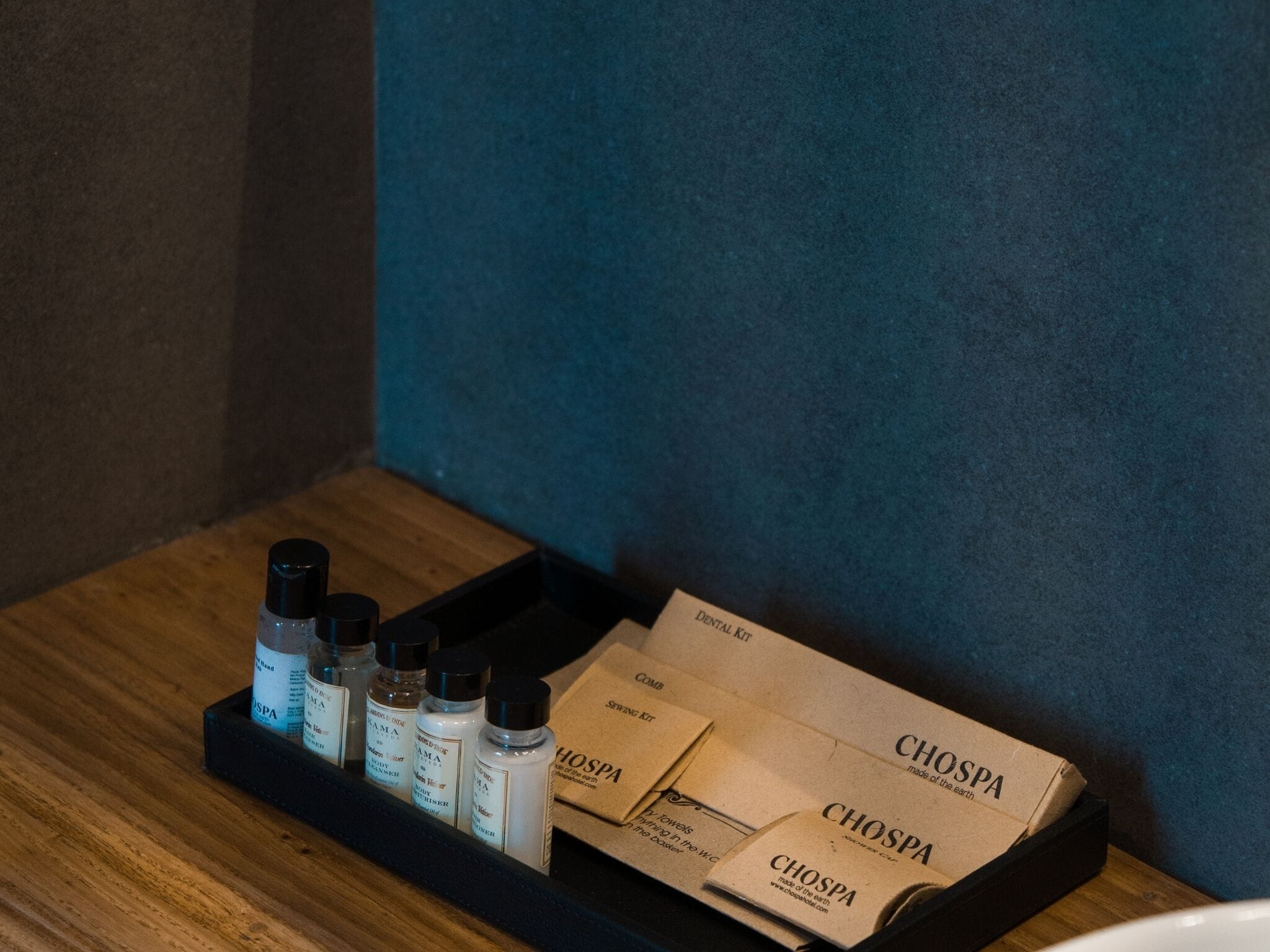 A wooden tray with several bottles and boxes labeled 'CHOSPA' on a wooden surface against a blue wall.