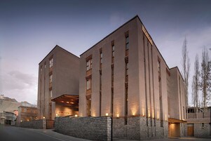 Un edificio moderno con fachada de piedra, ventanas grandes y un letrero que dice "CHOSPA".
