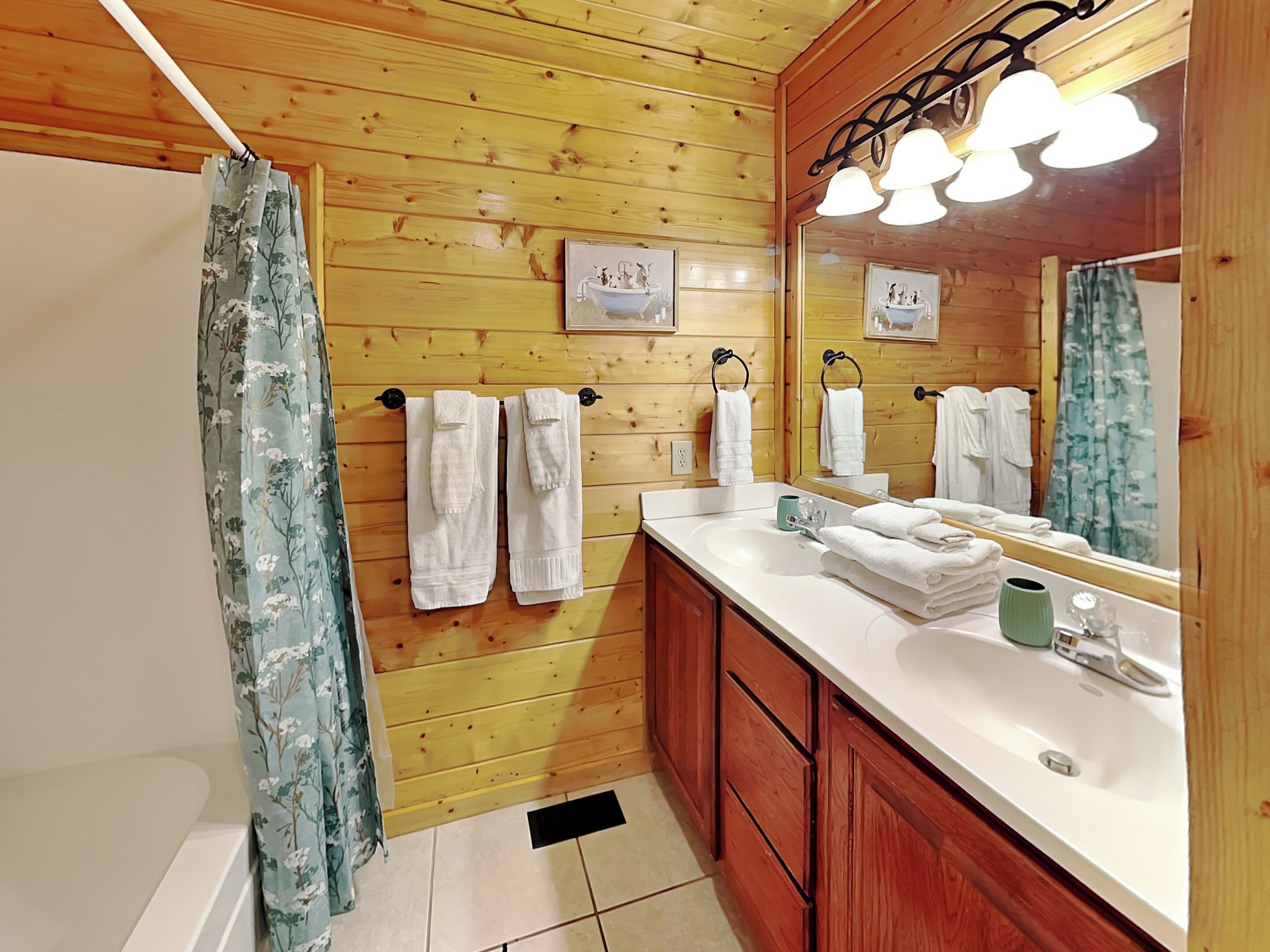 A wooden-paneled bathroom with a white sink, a mirror, and two towels hanging on hooks.