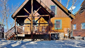 A log cabin with a porch, a satellite dish, and a sign indicating the address.