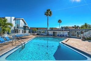 A swimming pool with blue tiles, surrounded by lounge chairs and palm trees. - Madeira Beach Yacht Club 151H by Distinctive Beach Rentals (Madeira Beach)