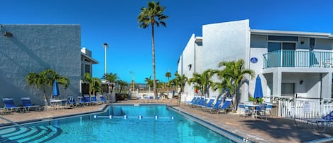 Une piscine à l’eau d’un bleu cristallin, entourée de chaises longues et de palmiers.