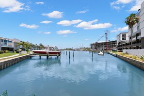 A canal with boats docked, modern buildings, and a clear sky. - Madeira Beach Yacht Club 151H by Distinctive Beach Rentals (Madeira Beach)