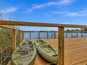 A wooden deck with two kayaks and a view of a calm lake.