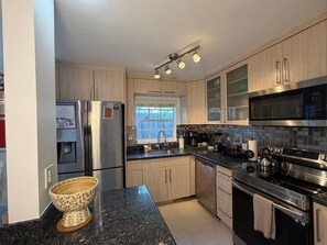 A modern kitchen with stainless steel appliances, a water dispenser, and a window providing natural light.