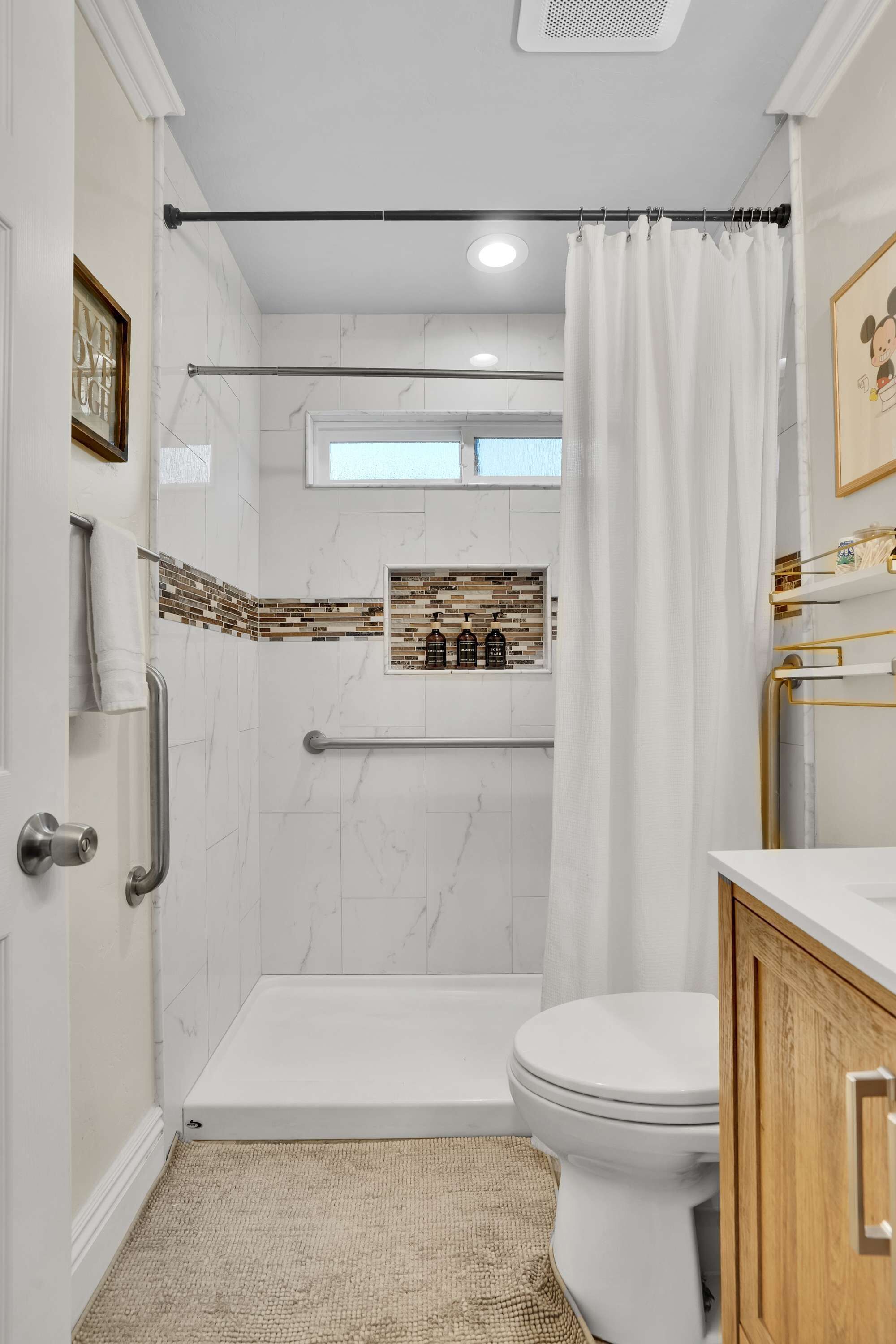 Un baño con ducha, inodoro y tocador.
