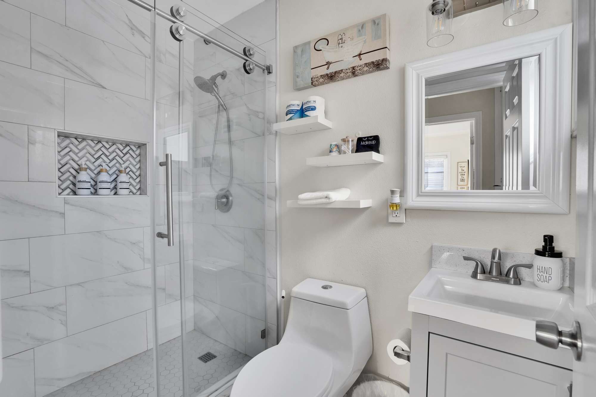 A modern bathroom with a glass-enclosed shower, a toilet, and a sink with hand soap.