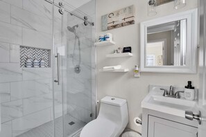 A modern bathroom with a glass-enclosed shower, a toilet, and a sink with hand soap. - Family Friendly Retreat, 10 minutes to Disney & Convention Center (Anaheim)