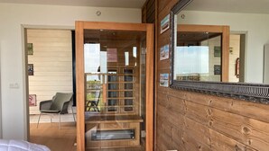 Une pièce avec un mur en bois, un lit, une chaise et une porte vitrée donnant sur un espace extérieur.