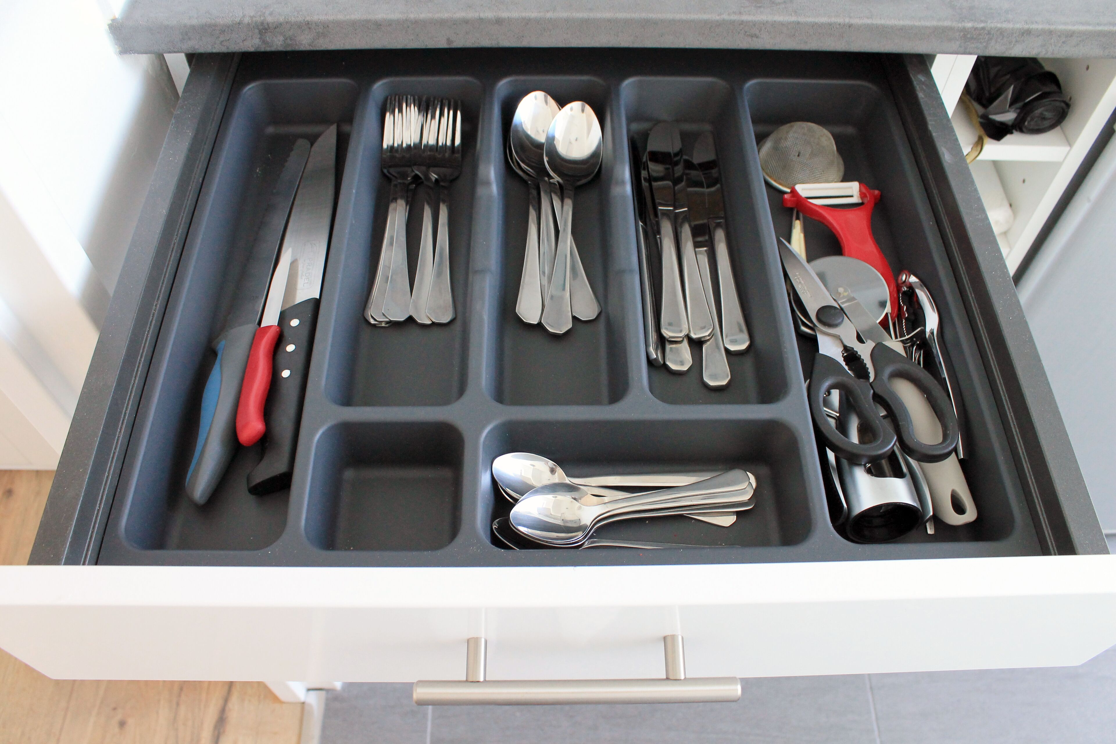 Un tiroir compartimenté contenant divers ustensiles et outils de cuisine.