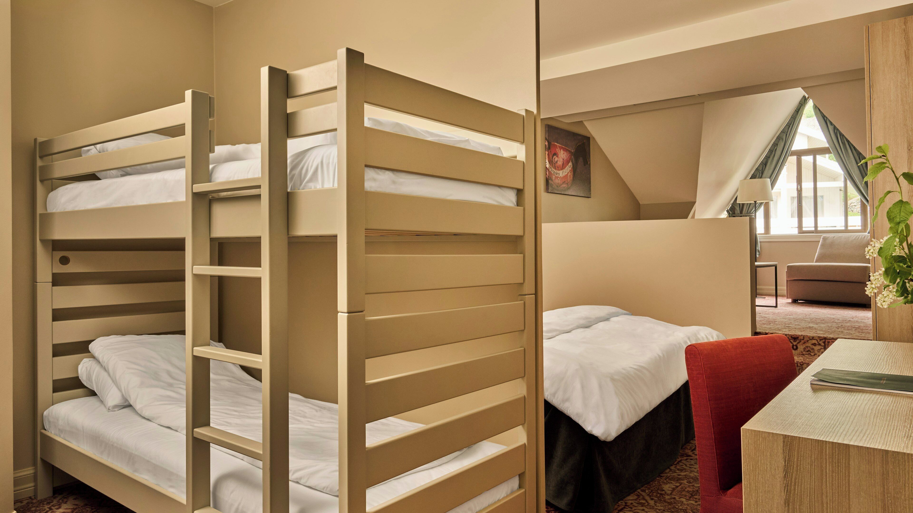 A room with bunk beds, a desk, and a chair.