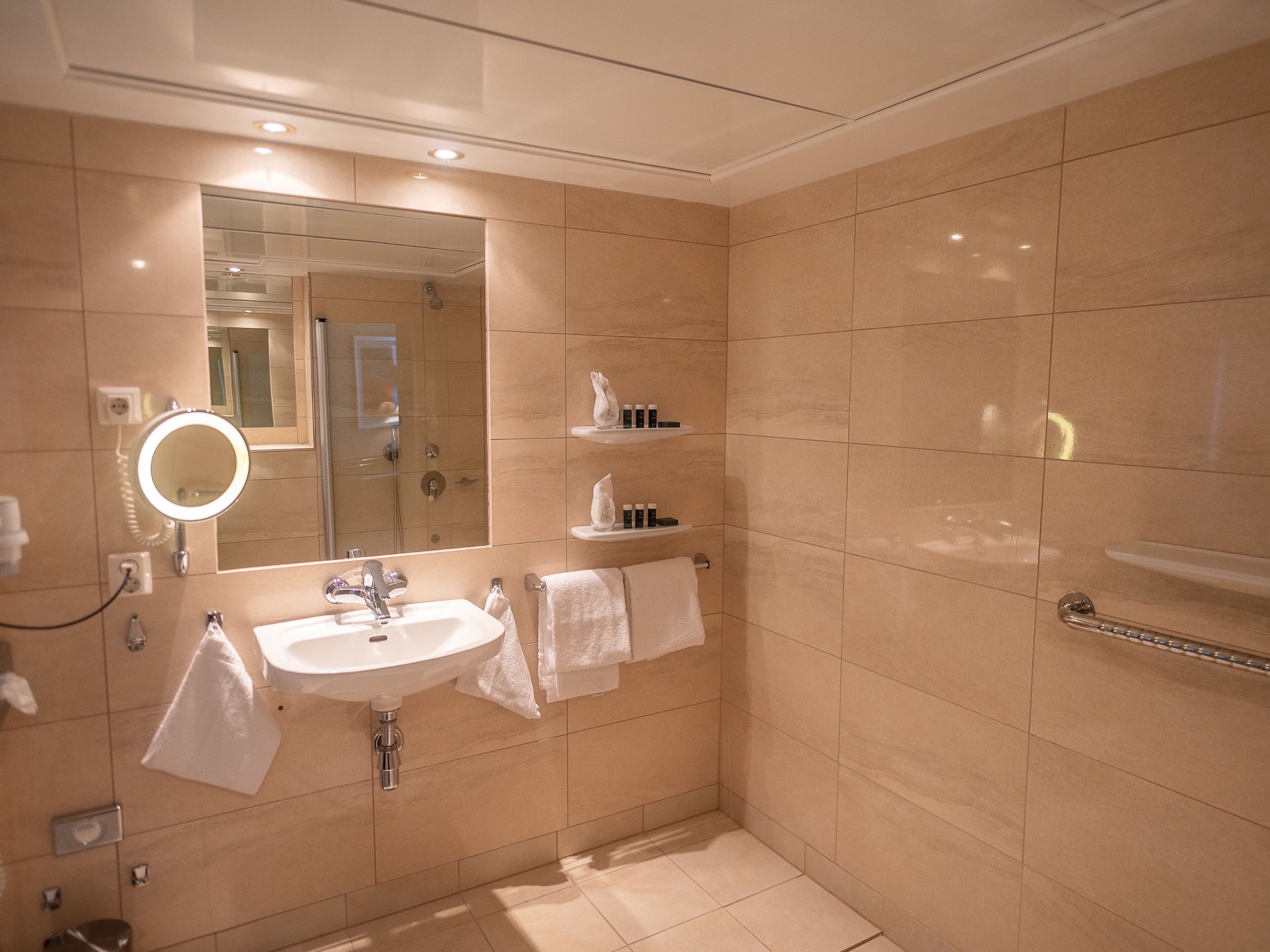 Un baño moderno con lavamanos, espejo e inodoro con ducha.