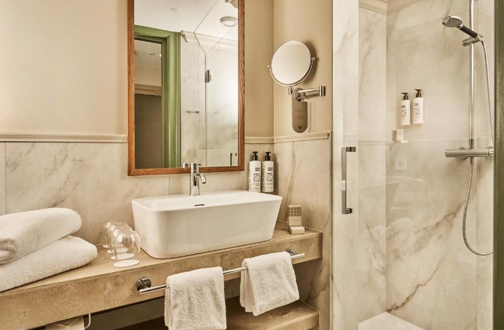 Ein Badezimmer mit einem großen Waschbecken, Spiegel und Dusche.