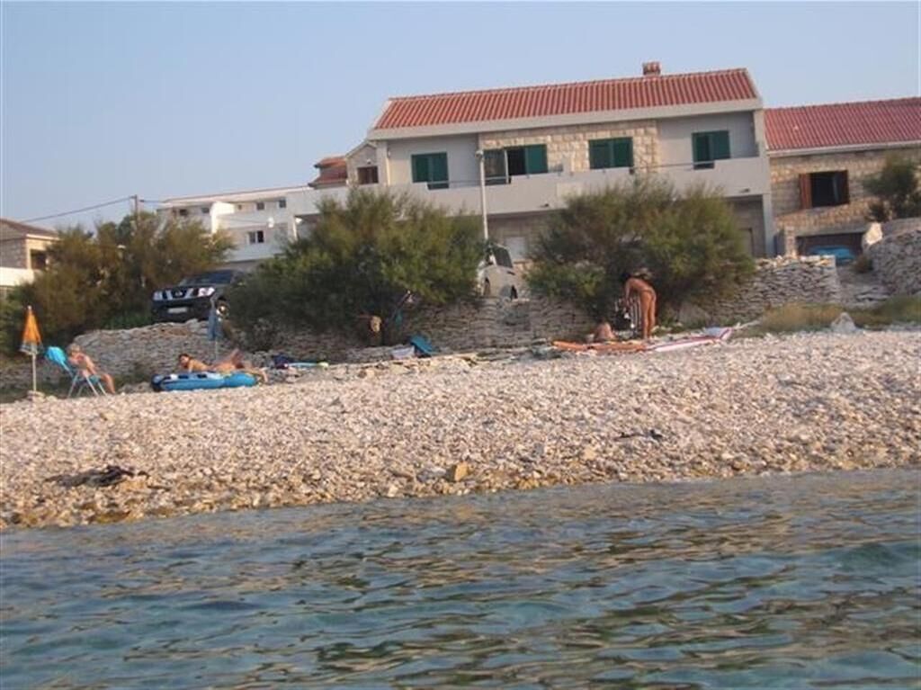 A beach with a rocky shore, a few people, and a building in the background.