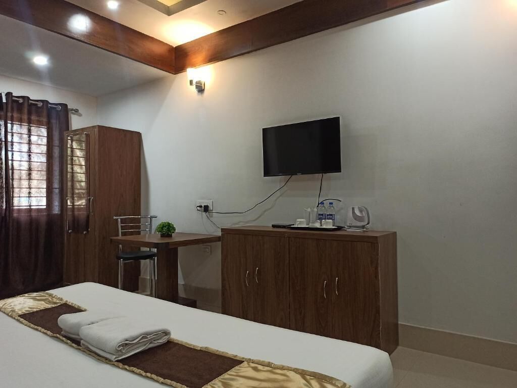 Una habitación de hotel con cama, escritorio, televisor y armario.