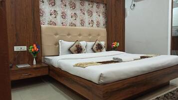 A bedroom with a wooden headboard, a bed with white bedding, and a floral-patterned wall.