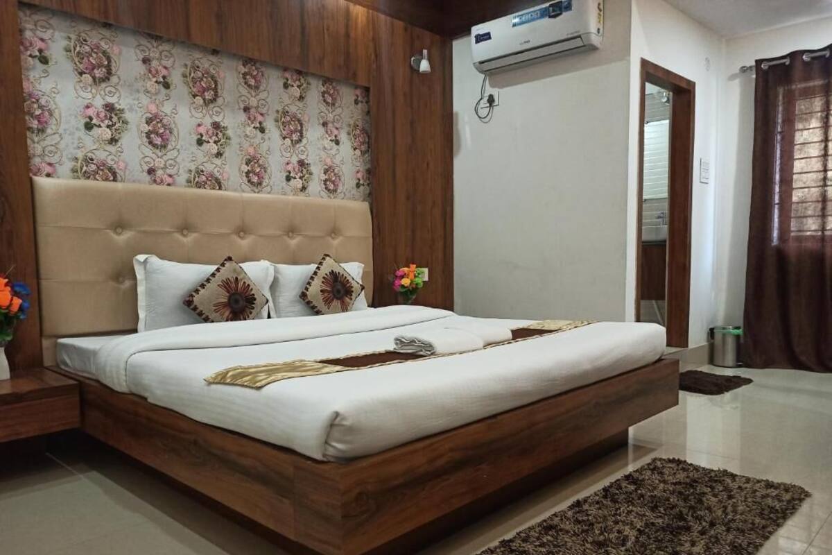 A bedroom with a wooden bed frame, a tufted headboard, and a floral-patterned wallpaper.