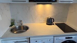 A kitchen with a stainless steel sink, a kettle, a microwave, and a dishwasher.