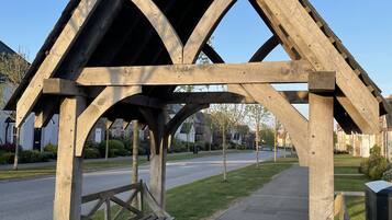 A wooden gazebo with a sloped roof and a bench underneath.