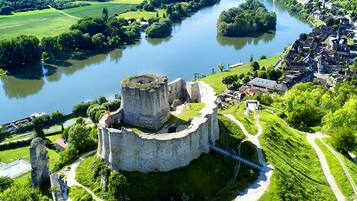 An aerial view of a historic castle surrounded by a moat, with a bridge leading to the entrance.