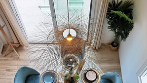Una sala de estar moderna con una araña central, sillones azules y una mesa de centro redonda.