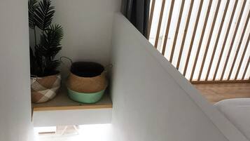 A staircase with a wooden railing, a potted plant, and a shelf with decorative items.