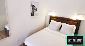 A hotel room with a bed, two bedside lamps, a wall-mounted plant, and a window.