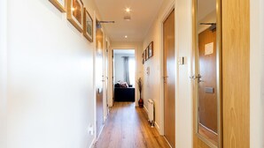 A hallway with wooden flooring, framed pictures on the walls, and wooden doors. - Modern, Spacious City Apartment, Lift, Balcony, Free Wi-fi & Parking, Fab views, (Edinburgh)