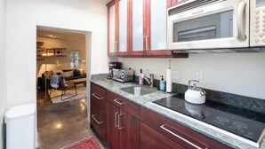 A modern kitchen with dark wooden cabinets, a stainless steel sink, and a built-in microwave. - Fiddler's Retreat by Kokopelli Property Management (Santa Fe)
