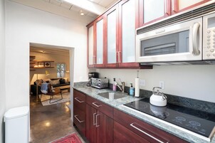 A modern kitchen with dark wooden cabinets, a stainless steel sink, and a built-in microwave.
