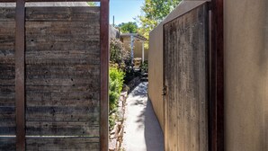 A narrow pathway leading to a building with a wooden door and a concrete wall. - Fiddler's Retreat by Kokopelli Property Management (Santa Fe)