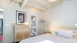 A bedroom with a large bed, a wardrobe, a mirror, and a bedside table with a lamp. - Fiddler's Retreat by Kokopelli Property Management (Santa Fe)
