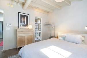 A bedroom with a large bed, a wardrobe, a mirror, and a bedside table with a lamp.