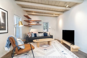 A modern living room with a sofa, coffee table, and TV stand.