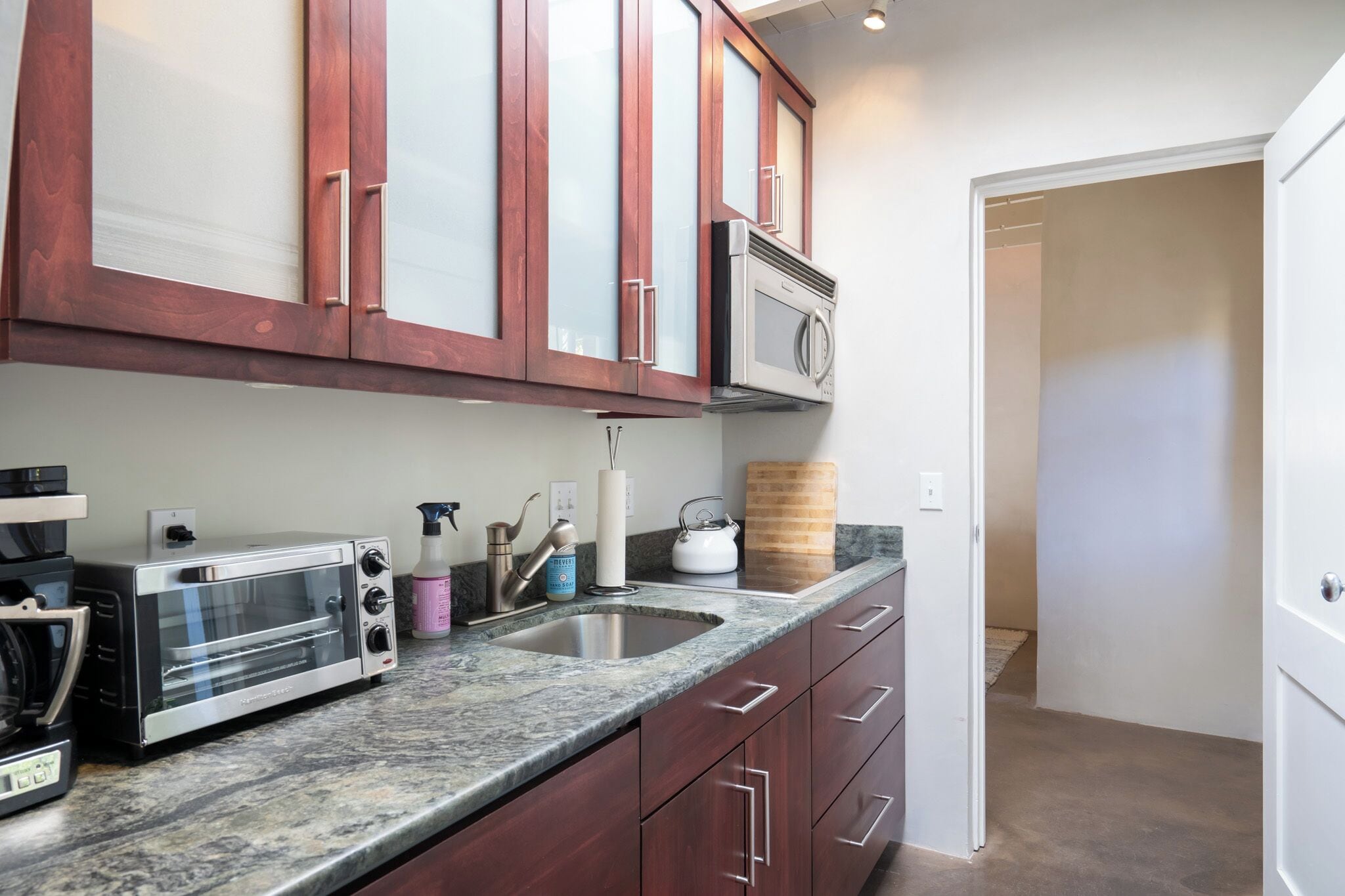 A kitchen with a built-in microwave, a toaster, and a sink.
